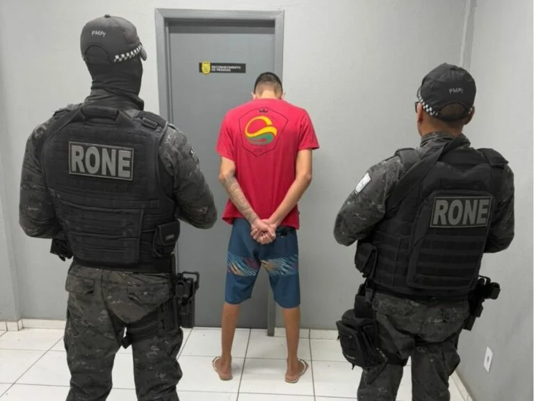 Dois policiais militares da RONE acompanham adolescente de costas, durante apreensão relacionada a investigação de homicídio em Teresina.