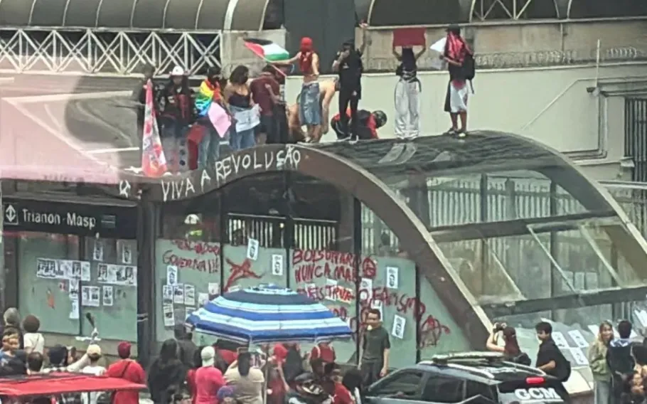 Pessoas sobre estrutura de acesso ao Metrô durante tumultos após manifestação de apoio a Lula na Avenida Paulista.