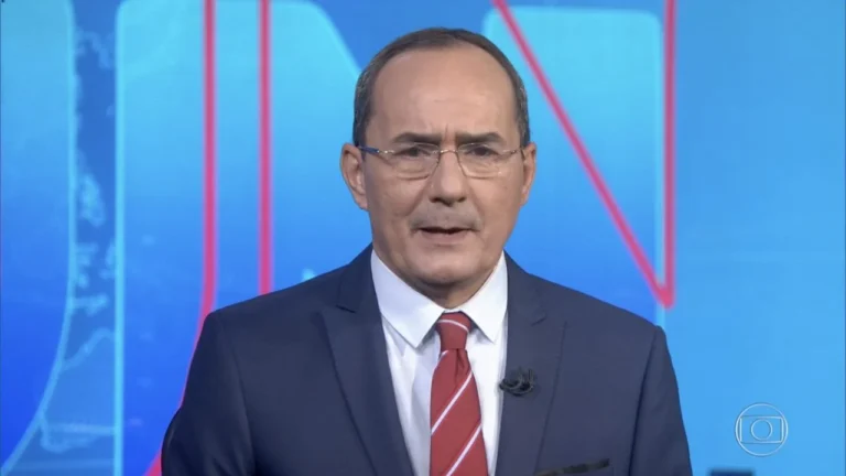 Jornalista Ayres Rocha usando terno azul e gravata vermelha durante participação no Jornal Nacional, da TV Globo, em 2019.