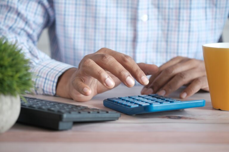 Pessoa utiliza calculadora e comprovantes para organizar despesas domésticas em meio ao aumento do endividamento no Brasil.