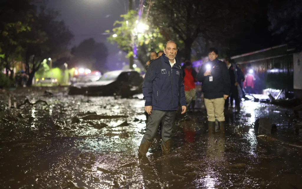 Autoridades percorrem rua coberta de lama após enxurrada atingir Las Condes, em Santiago, no Chile.