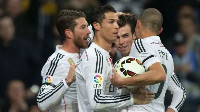 Cristiano Ronaldo com uniforme branco do Real Madrid, acompanhado por Sergio Ramos e outros jogadores durante uma partida.