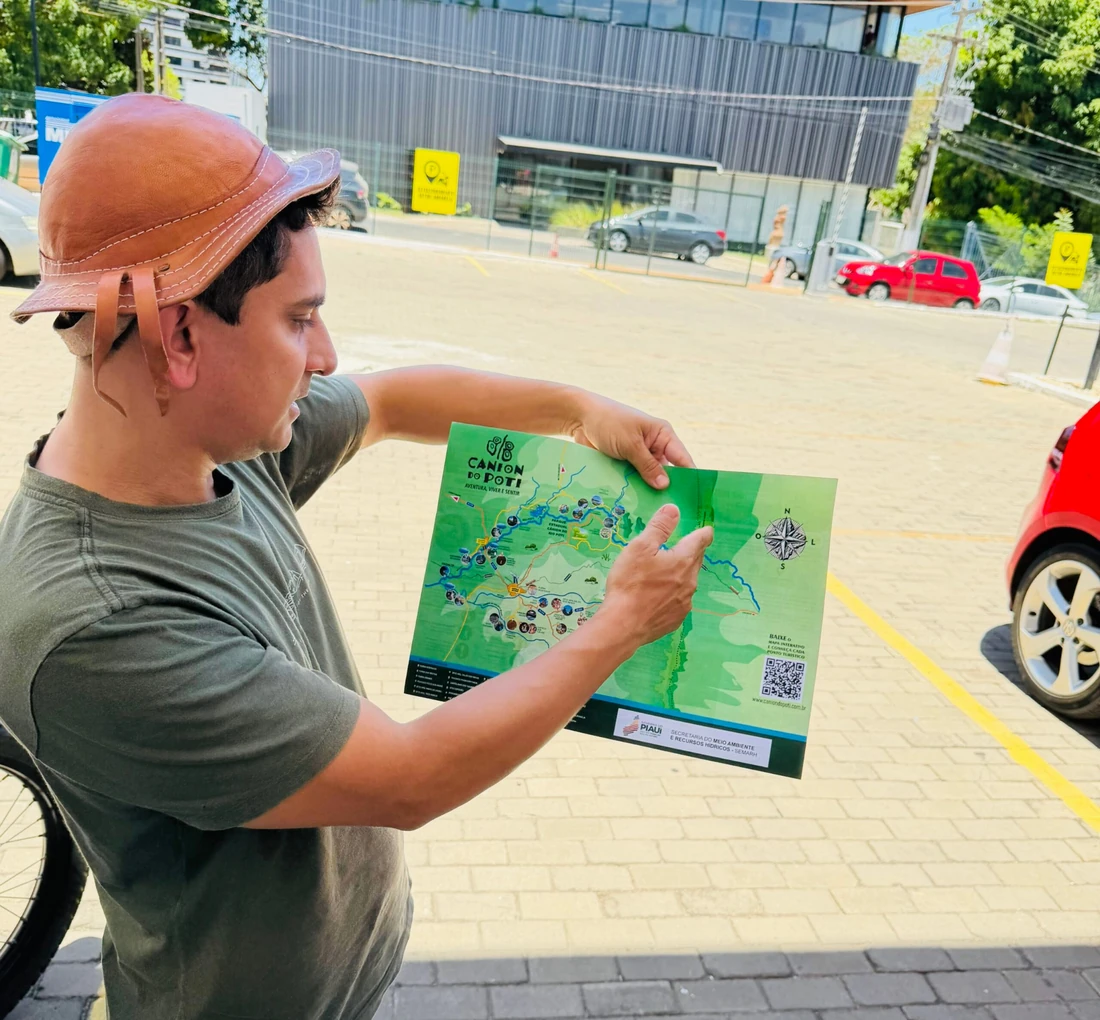 Dionísio Carvalho segura e aponta um mapa ilustrado do Cânion do Rio Poti.