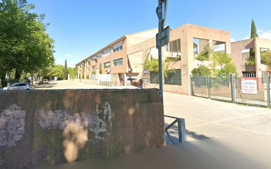 Área externa da escola Joseph-Lakanal, em Aubagne, na França, com prédio, muro, grades e árvores.