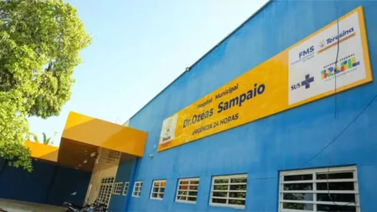 Fachada azul do Hospital Dr. Ozéas Sampaio, em Teresina, com placa amarela, janelas e entrada coberta.