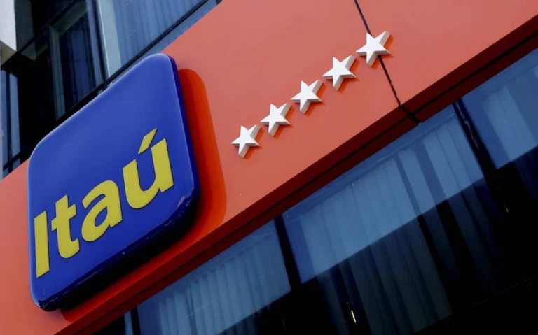Fachada do banco Itaú com letreiro azul e amarelo, cinco estrelas brancas sobre uma faixa laranja e janelas de vidro.