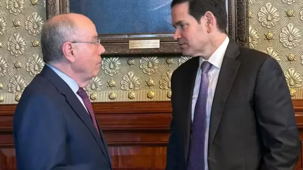 Mauro Vieira, à esquerda, e Marco Rubio conversam frente a frente, vestidos de terno, em uma sala com papel de parede ornamentado.