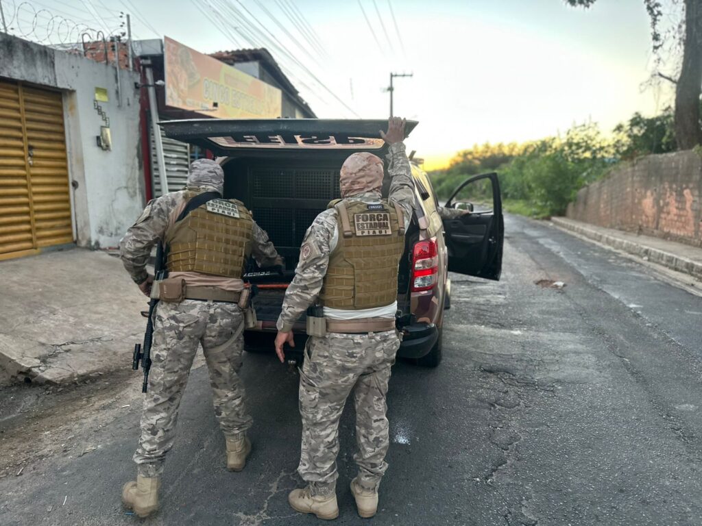 Agentes da Força Estadual Integrada de Segurança Pública do Piauí durante ação policial junto a uma viatura.