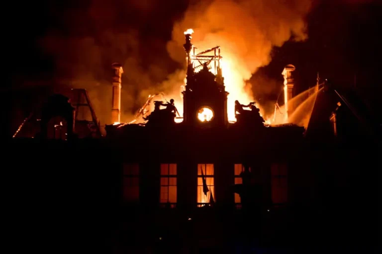 Torre e telhado da prefeitura de Limoges envolvidos por chamas durante a noite, com fumaça intensa e jatos de água dos bombeiros.