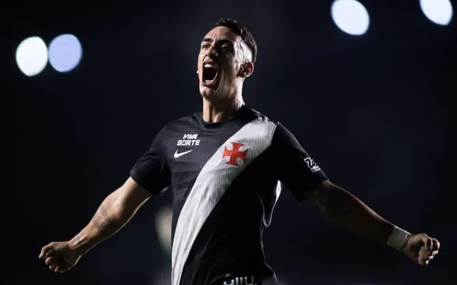 Puma Rodríguez, com a camisa preta do Vasco, grita e abre os braços em comemoração, diante de um fundo escuro.