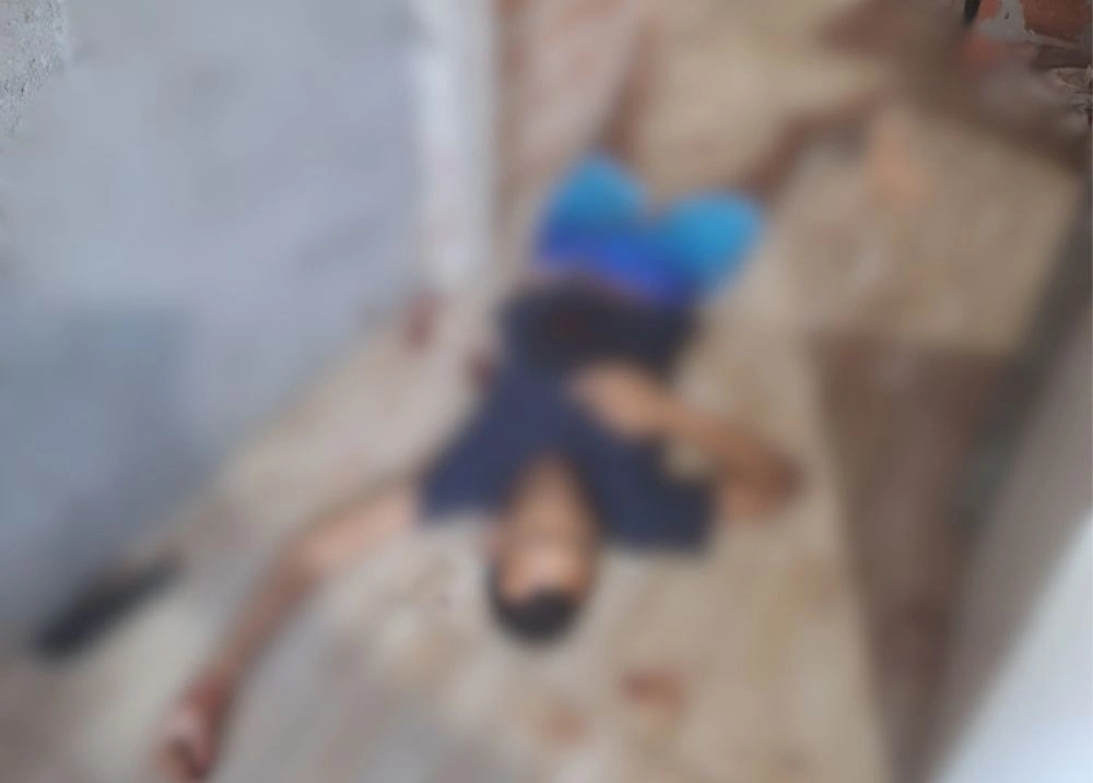 Imagem desfocada mostra o corpo de um homem caído no chão de uma residência após homicídio na zona Norte de Teresina.