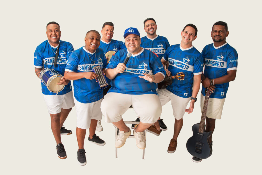 Seis músicos do projeto Samba no Coreto, vestidos com camisas azuis e acompanhados de instrumentos musicais, em fotografia de divulgação.