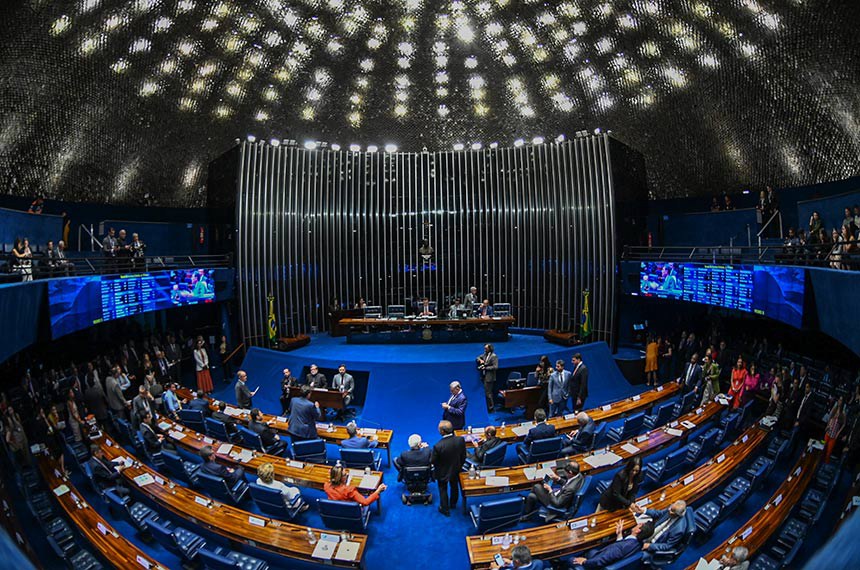 Vista ampla do plenário do Senado Federal, com parlamentares, bancadas em semicírculo, mesas da presidência e painéis eletrônicos azuis.