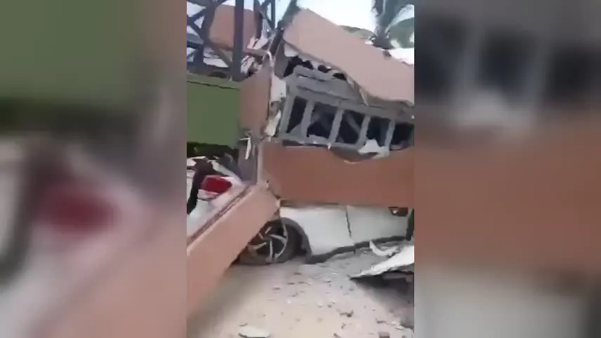 Estruturas de construção danificadas, com paredes destruídas e escombros espalhados pelo chão.