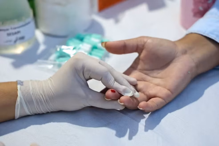 Profissional de saúde realiza coleta de sangue para teste rápido em ação de saúde pública.