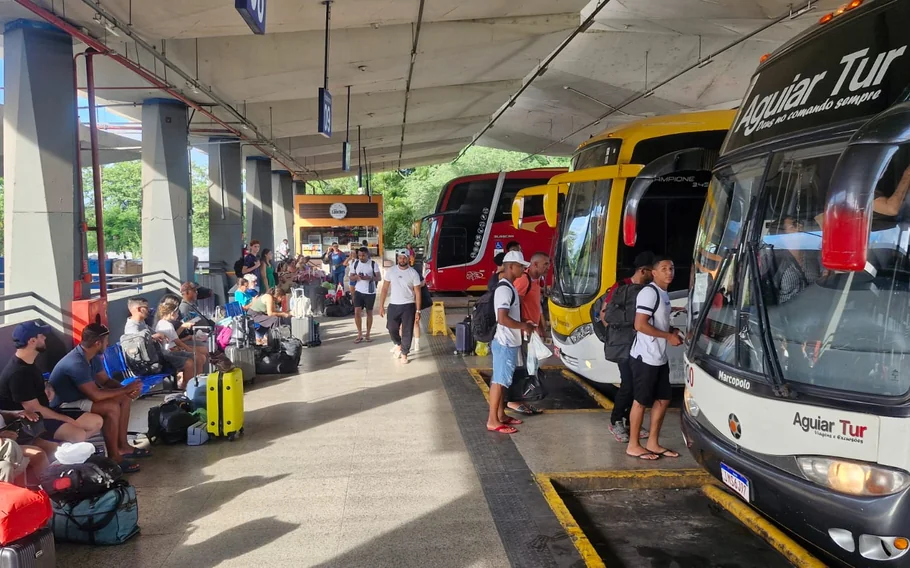 Plataforma da Rodoviária de Teresina com ônibus estacionados, passageiros aguardando embarque e bagagens ao lado dos bancos.