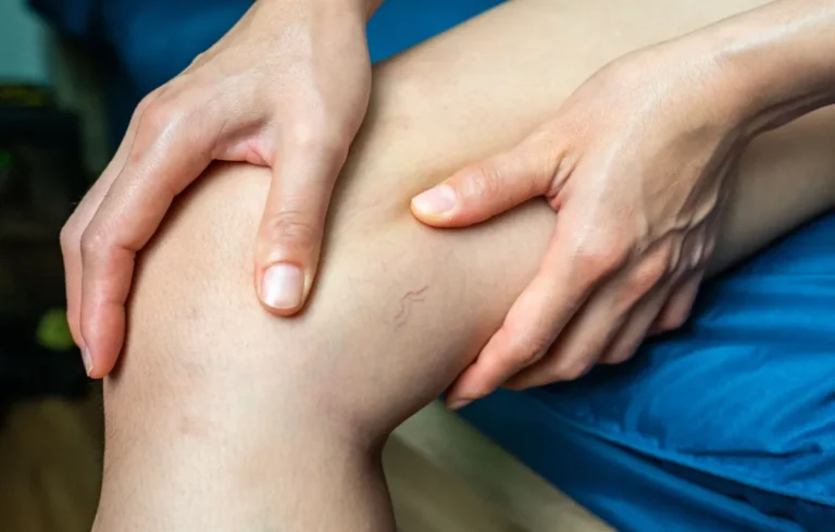 Pessoa sentada segura a perna com as duas mãos na região do joelho.