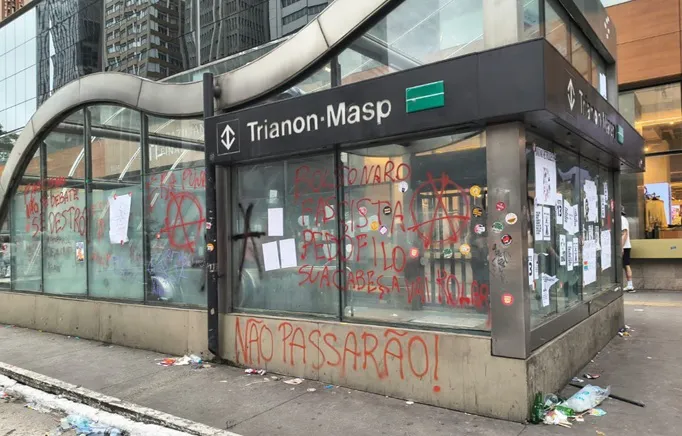 Entrada da estação Trianon-Masp, na Avenida Paulista, com pichações vermelhas nas paredes e nos vidros após manifestação.