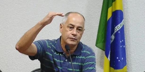 José Maria de Almeida, conhecido como Zé Maria, gesticula diante de uma bandeira do Brasil.