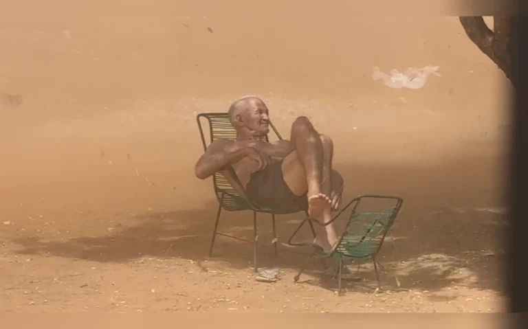 José Borges, o Zezé, de 80 anos, permanece sentado em uma cadeira debaixo de uma árvore, cercado pela poeira de um redemoinho em Picos (PI).